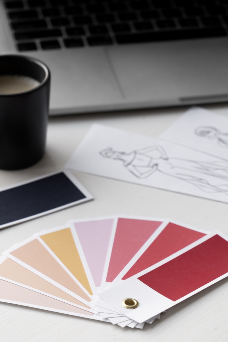 Paleta de cores e esboços sobre a mesa, ao lado do notebook